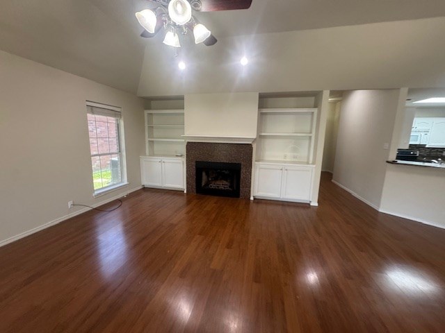 55 Southridge Dr, San Angelo, TX 76904 - unfurnished living room featuring lofted ceiling, a ceiling fan, dark wood-type flooring, a tile fireplace, and baseboards