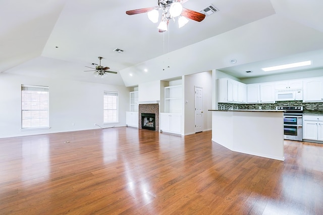 55 Southridge Dr, San Angelo, TX 76904 - unfurnished living room featuring a ceiling fan, light wood-style floors, a tile fireplace, built in shelves, and high vaulted ceiling
