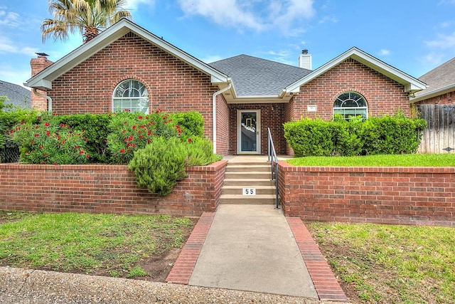 55 Southridge Dr, San Angelo, TX 76904 - view of front of house featuring a chimney, brick siding, and roof with shingles