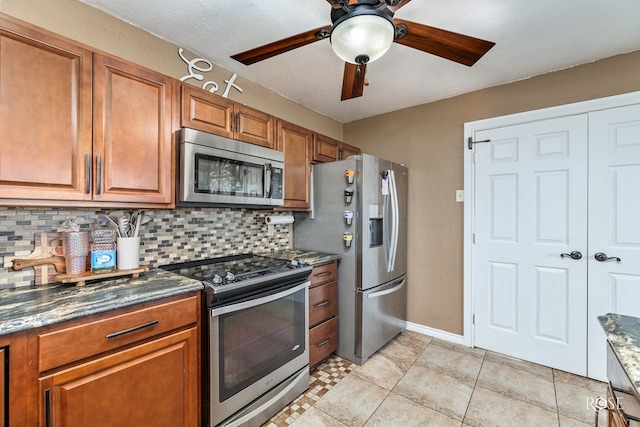 kitchen featuring tasteful backsplash, dark stone countertops, light tile patterned floors, ceiling fan, and stainless steel appliances