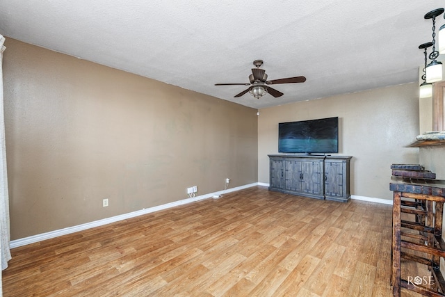 unfurnished living room featuring ceiling fan, light hardwood / wood-style floors, and a textured ceiling