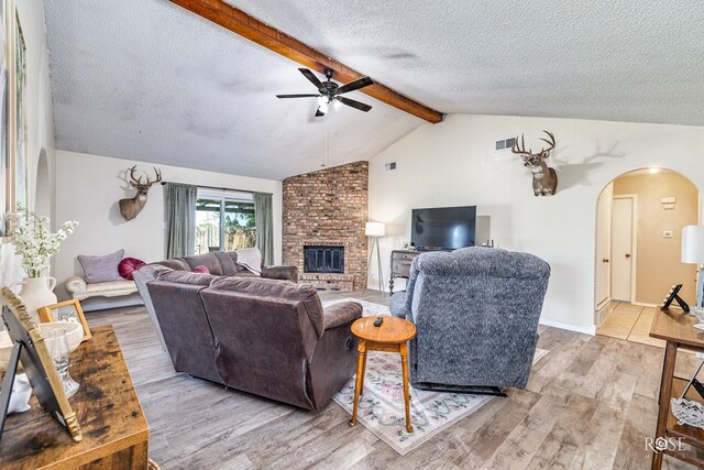 213 Amistad Rd, San Angelo, TX 76901 - living area featuring arched walkways, ceiling fan, light wood-style flooring, a textured ceiling, and a fireplace