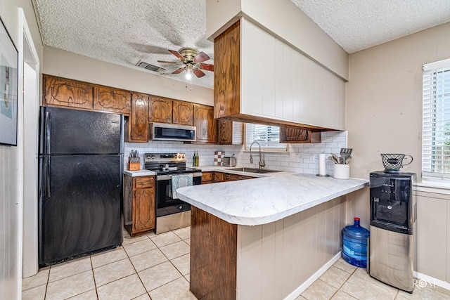 213 Amistad Rd, San Angelo, TX 76901 - kitchen with stainless steel appliances, a peninsula, a textured ceiling, light tile patterned floors, and a ceiling fan