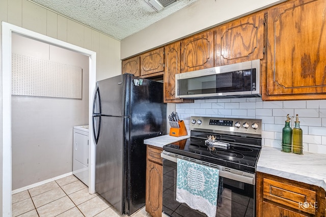213 Amistad Rd, San Angelo, TX 76901 - kitchen with appliances with stainless steel finishes, brown cabinetry, washer / clothes dryer, backsplash, and a textured ceiling
