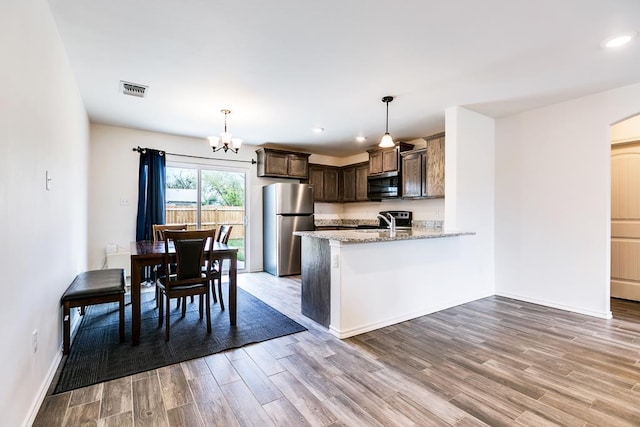 kitchen featuring dark brown cabinetry, light wood-type flooring, a peninsula, an inviting chandelier, and stainless steel appliances