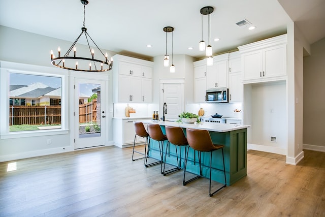 3609 Clearview Dr, San Angelo, TX 76904 - kitchen with stainless steel microwave, light countertops, light wood finished floors, white cabinets, and recessed lighting