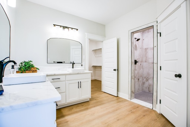 3609 Clearview Dr, San Angelo, TX 76904 - full bathroom with wood finished floors, a shower stall, double vanity, and a walk in closet