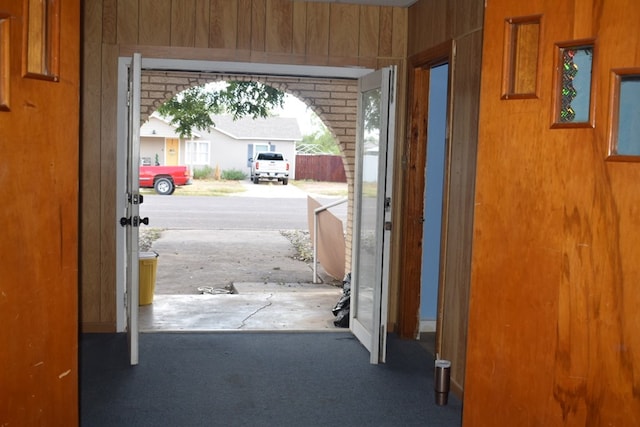 doorway to outside with wood walls