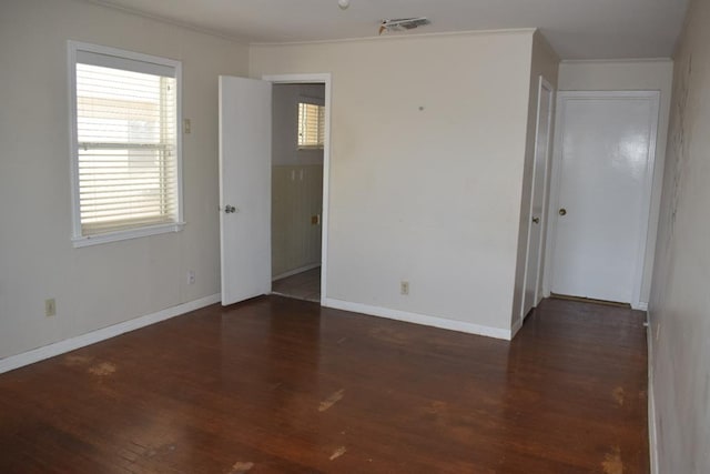 empty room featuring ornamental molding, dark hardwood / wood-style flooring, and a wealth of natural light