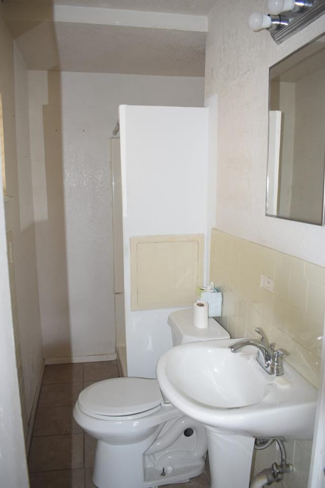 bathroom with tile patterned floors, toilet, sink, and backsplash