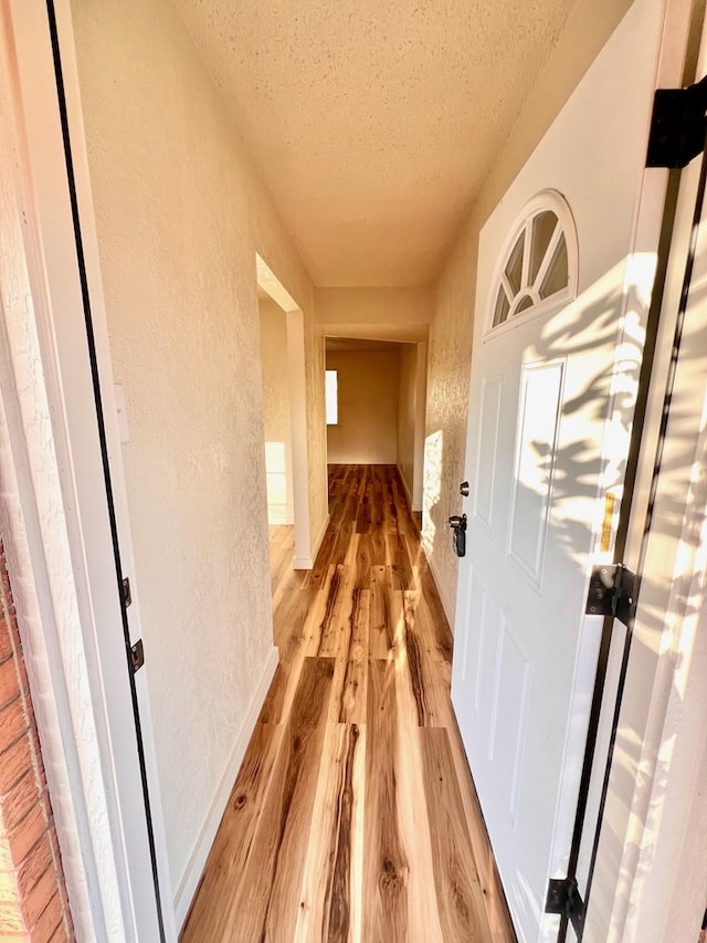2726 Erline Dr, San Angelo, TX 76901 - hallway with a textured wall, a textured ceiling, and light wood-type flooring