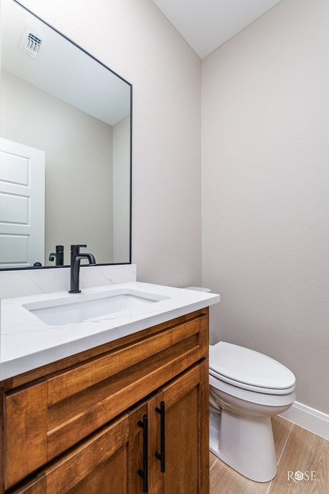 2301 Hillside Dr, San Angelo, TX 76904 - half bath with wood finished floors, vanity, toilet, and baseboards