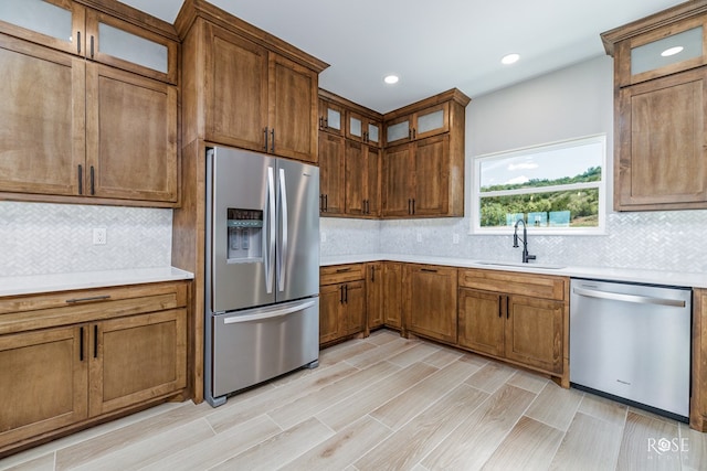 2301 Hillside Dr, San Angelo, TX 76904 - kitchen with stainless steel appliances, a sink, decorative backsplash, light countertops, and brown cabinets