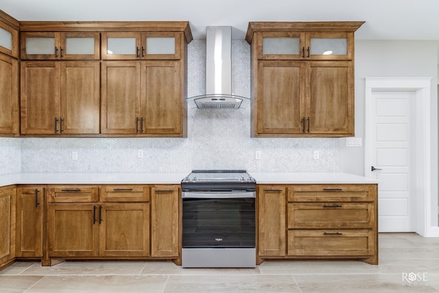 2301 Hillside Dr, San Angelo, TX 76904 - kitchen with wall chimney exhaust hood, stainless steel stove, brown cabinetry, and light countertops