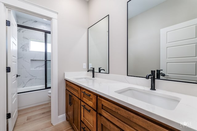 2301 Hillside Dr, San Angelo, TX 76904 - bathroom featuring toilet, double vanity, combined bath / shower with glass door, and wood finished floors