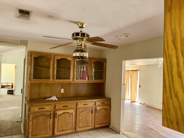 165 Edinburgh Rd, San Angelo, TX 76901 - interior space with glass insert cabinets, a textured ceiling, visible vents, brown cabinetry, and ceiling fan