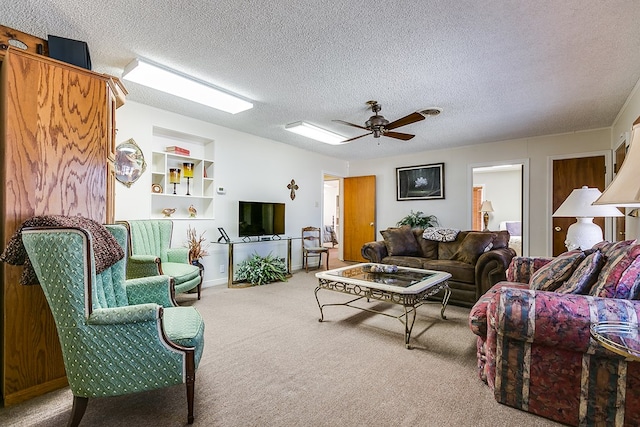 living room featuring ceiling fan, carpet floors, a textured ceiling, and built in shelves