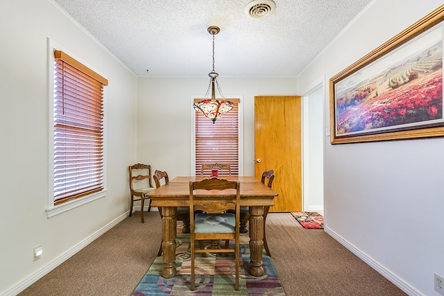 carpeted dining area with ornamental molding and a textured ceiling