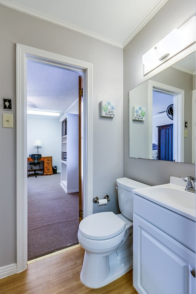 bathroom with vanity, crown molding, wood-type flooring, and toilet