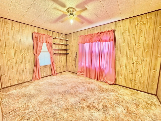 spare room featuring wooden walls, ceiling fan, and carpet flooring