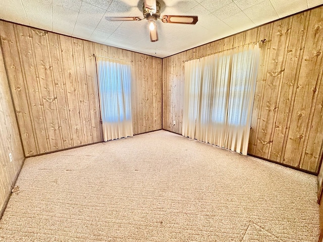 spare room with a healthy amount of sunlight, light carpet, and wood walls