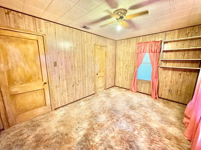 unfurnished room featuring wooden walls and ceiling fan