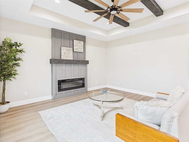 1942 Pine Valley St, San Angelo, TX 76904 - living room with a tray ceiling, light wood-type flooring, a ceiling fan, and a glass covered fireplace