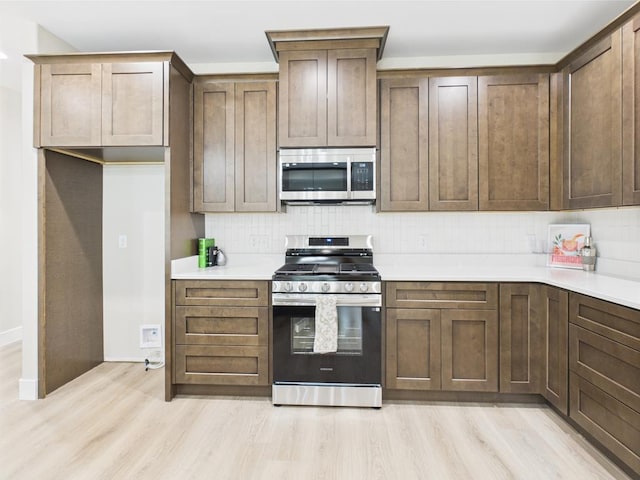 1942 Pine Valley St, San Angelo, TX 76904 - kitchen with appliances with stainless steel finishes, light wood-type flooring, decorative backsplash, and light countertops
