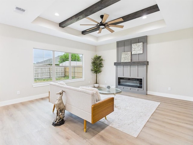 1942 Pine Valley St, San Angelo, TX 76904 - living room featuring a tray ceiling, light wood finished floors, ceiling fan, a glass covered fireplace, and beam ceiling