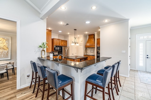 2141 Valleyview Dr, San Angelo, TX 76904 - kitchen featuring black appliances, brown cabinetry, premium range hood, baseboards, and decorative backsplash