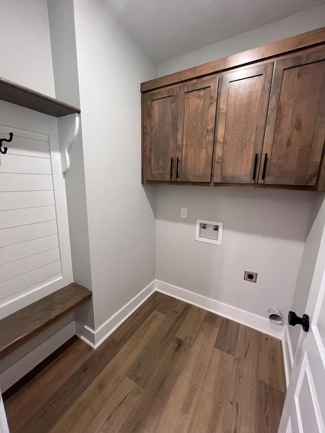 washroom with electric dryer hookup, hookup for a washing machine, dark hardwood / wood-style flooring, and cabinets