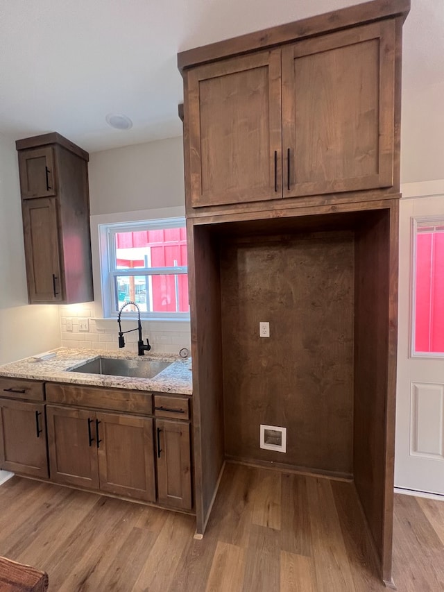 kitchen with light stone counters, light hardwood / wood-style floors, sink, and tasteful backsplash