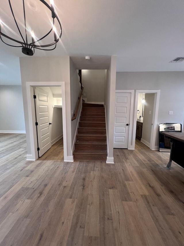 stairway featuring an inviting chandelier and wood-type flooring