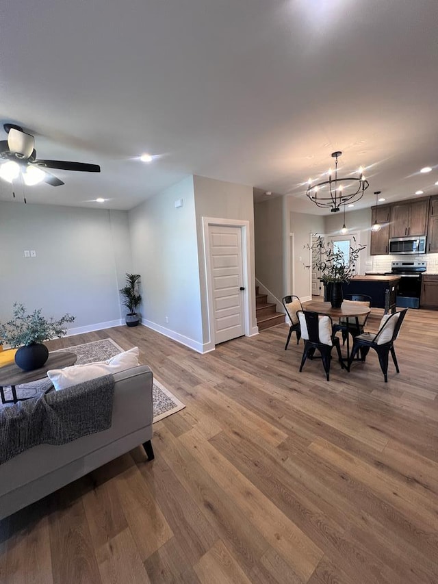 living room featuring ceiling fan with notable chandelier and hardwood / wood-style floors