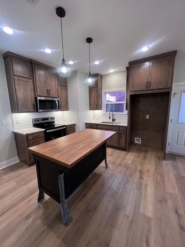 kitchen featuring black electric range oven, sink, hanging light fixtures, dark brown cabinetry, and light wood-type flooring