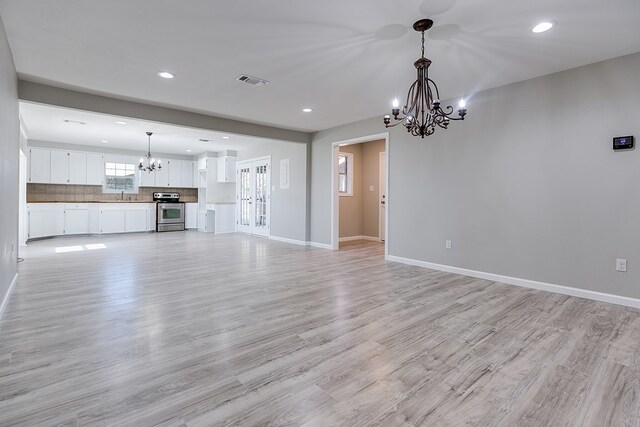 unfurnished living room featuring sink, an inviting chandelier, and light hardwood / wood-style flooring