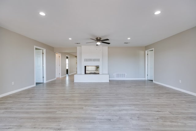 unfurnished living room with a brick fireplace and ceiling fan