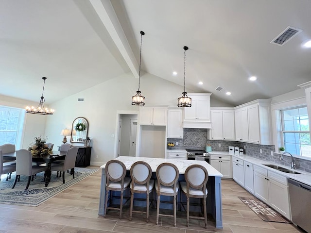 kitchen featuring pendant lighting, sink, stainless steel appliances, white cabinets, and a kitchen island