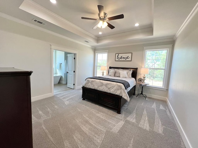 carpeted bedroom with ceiling fan, ensuite bathroom, a raised ceiling, and multiple windows