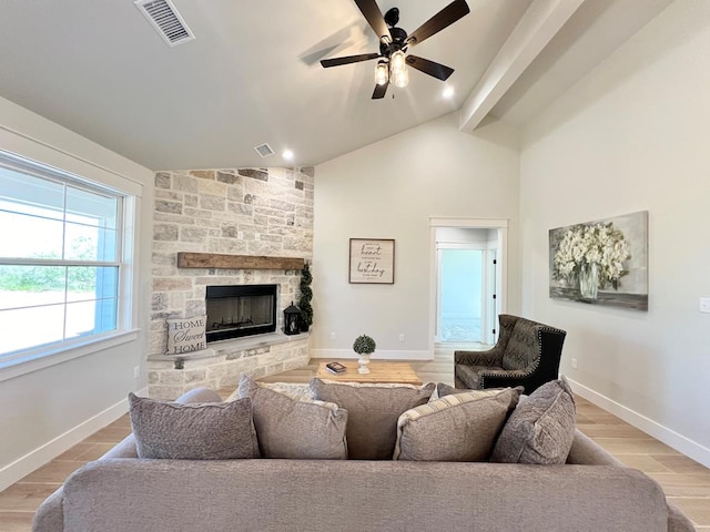 living room with a stone fireplace, vaulted ceiling, light hardwood / wood-style floors, and ceiling fan