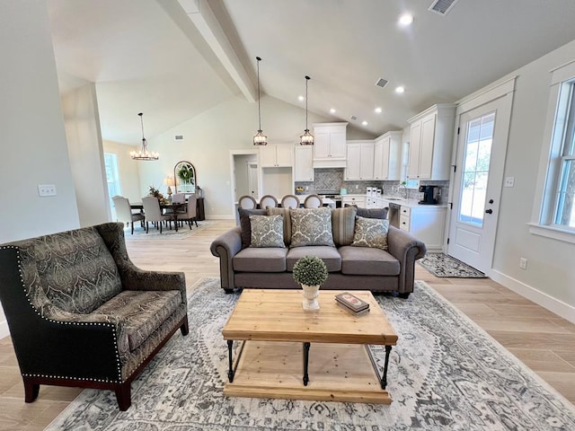 living room featuring sink, lofted ceiling with beams, a chandelier, and light wood-type flooring