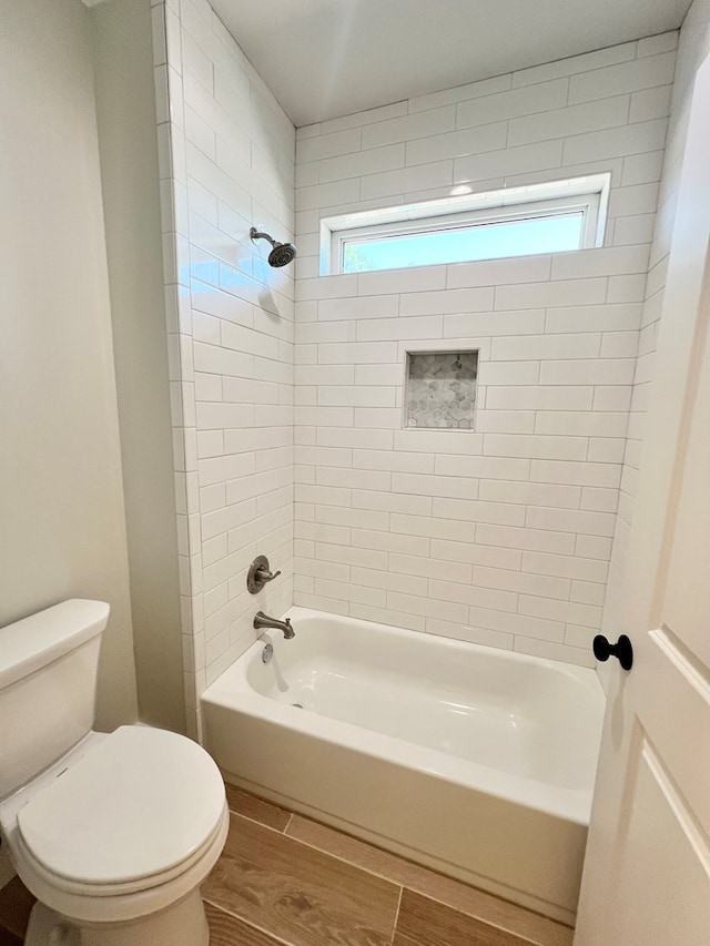 bathroom featuring toilet and tiled shower / bath