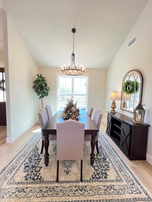 dining space featuring lofted ceiling, a notable chandelier, and light hardwood / wood-style flooring