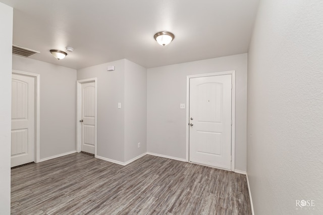 spare room featuring visible vents, baseboards, and wood finished floors