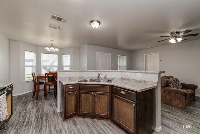 kitchen featuring dark brown cabinetry, visible vents, a sink, and wood finished floors