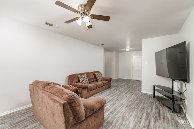 living room featuring a ceiling fan, wood finished floors, visible vents, and baseboards