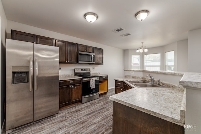 kitchen with visible vents, appliances with stainless steel finishes, light countertops, dark brown cabinets, and a sink