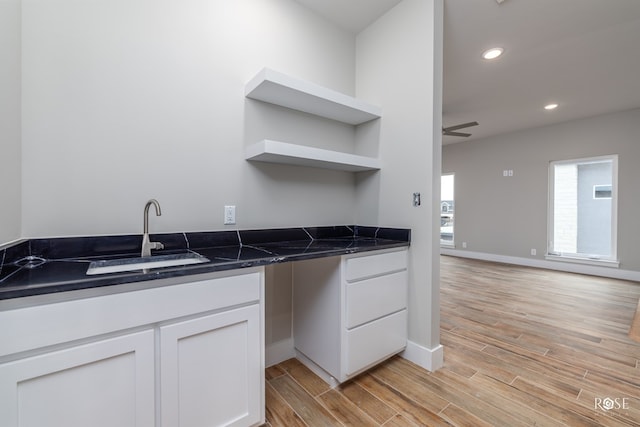 kitchen featuring white cabinetry, ceiling fan, dark stone counters, and sink