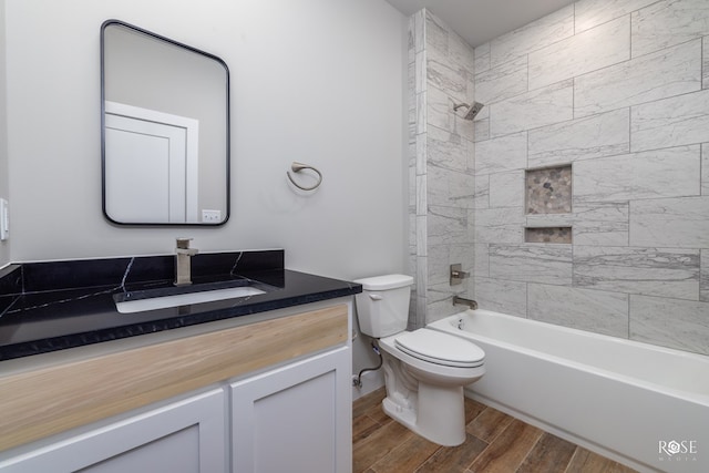 full bathroom with tiled shower / bath, wood-type flooring, vanity, and toilet