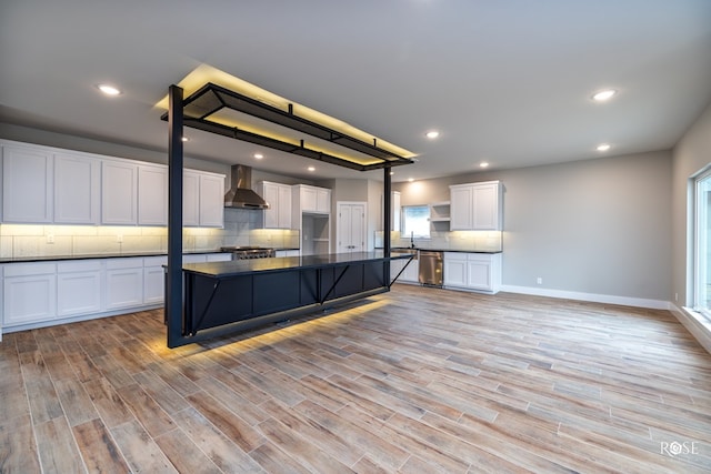 kitchen featuring white cabinetry, a center island, light hardwood / wood-style flooring, and wall chimney range hood